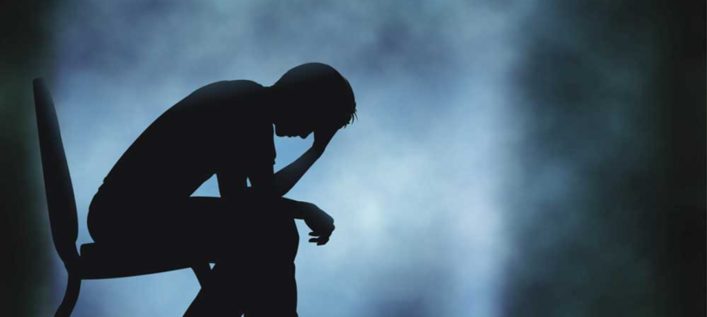 Depresyon yaşayan düşünceli kişinin karanlık ortamda otururken silüeti